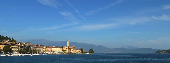 FerienhausGranCanaria beliebte Urlaubsziele am Gardasee -  Mit einer Fläche von 370 km² ist der Gardasee der größte See Italiens. Es liegt am Fuße der Alpen und erstreckt sich über drei Staaten: Lombardei, Venetien und Trentino. Die maximale Tiefe des Sees beträgt 346 m, er hat eine längliche Form und sein nördliches Ende ist sehr schmal. Dort ist der See von den Bergen der Gruppo di Baldo umgeben. Du trittst aus deinem gemütlichen Hotelzimmer und es begrüßt dich die warme italienische Sonne. Du blickst auf den atemberaubenden Gardasee, der in zahlreichen Blautönen schimmert - von tiefem Dunkelblau bis zu funkelndem Türkis. Majestätische Berge umgeben dich, während die Brise sanft deine Haut streichelt und der Duft von blühenden Zitronenbäumen deine Nase kitzelt. Du schlenderst die malerischen, engen Gassen entlang, vorbei an farbenfrohen, blumengeschmückten Häusern. Vereinzelt unterbricht das fröhliche Lachen der Einheimischen die friedvolle Stille. Du fühlst dich wie in einem Traum, der nicht enden will. Jeder Schritt führt dich zu neuen Entdeckungen und Abenteuern. Du probierst die köstliche italienische Küche mit ihren frischen Zutaten und verführerischen Aromen. Die Sonne geht langsam unter und taucht den Himmel in ein leuchtendes Orange-rot - ein spektakulärer Anblick.